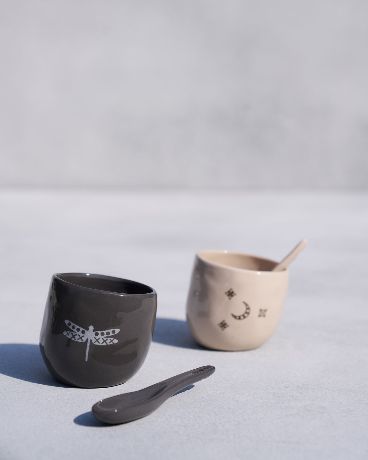 Pair of Taramandal ceramic pots with matching spoons side by side.
