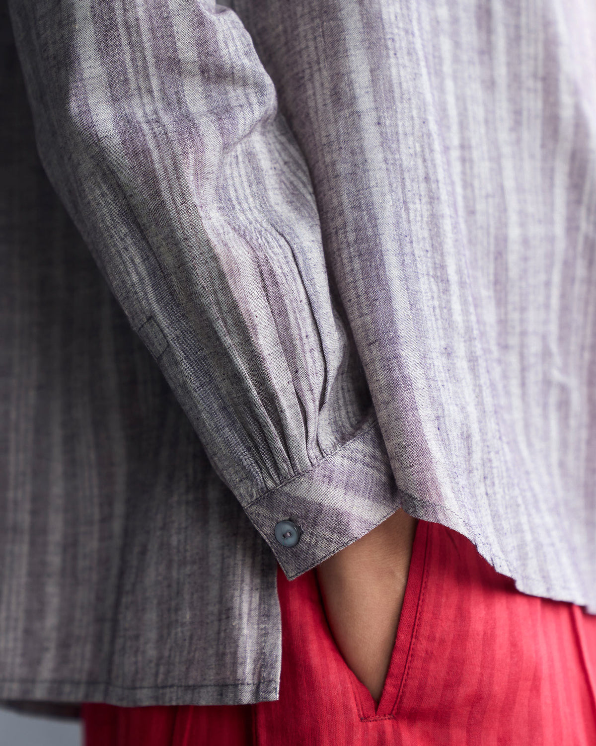 Close-up of a grey striped mandarin collar top sleeve cuff and side slit.