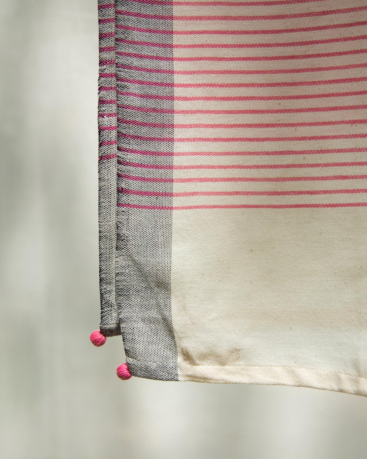 Close-up of Coast Towel corner showing its pink stripes and pom-pom tassel.