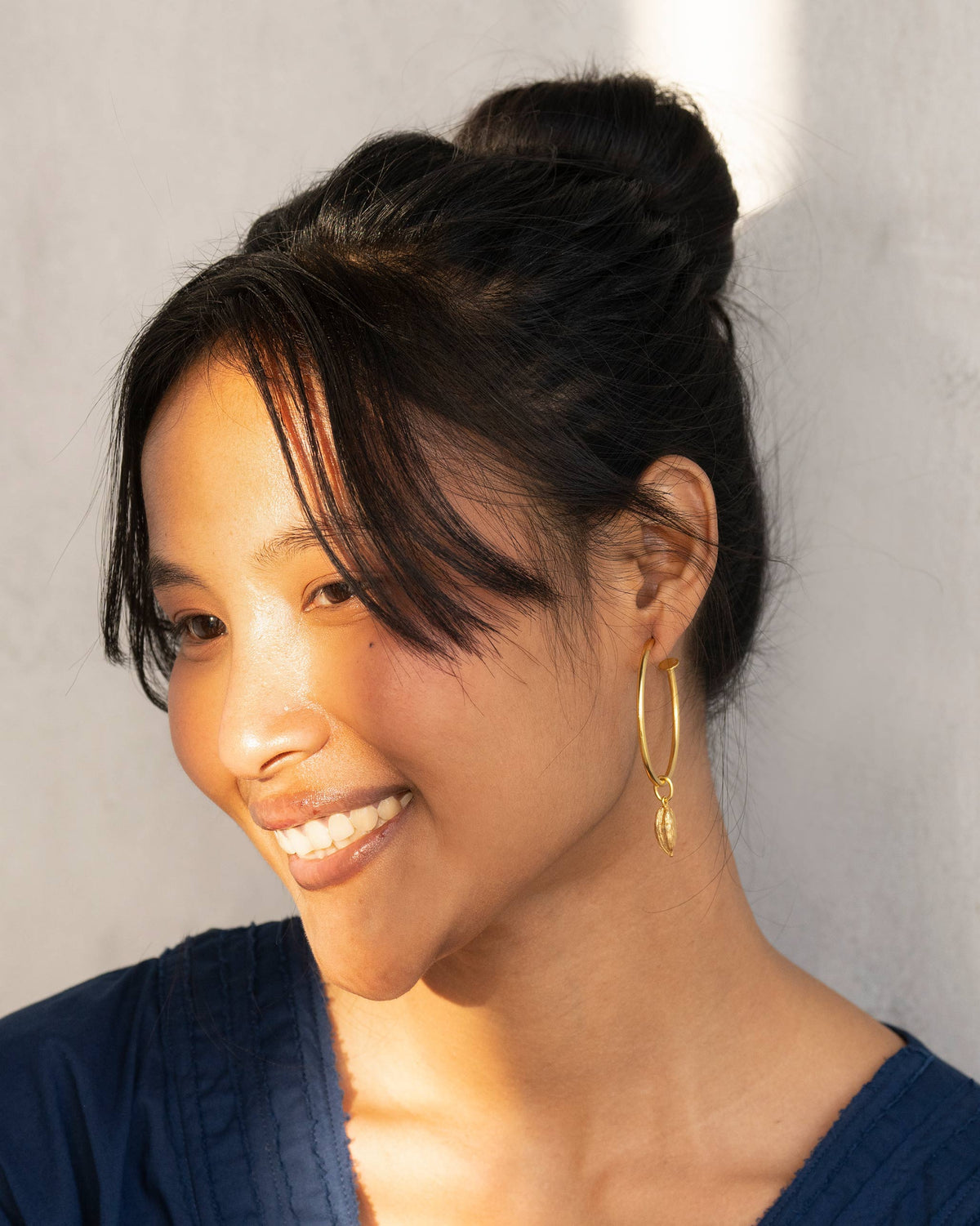 Large gold hoop earring with a shell charm worn in profile.