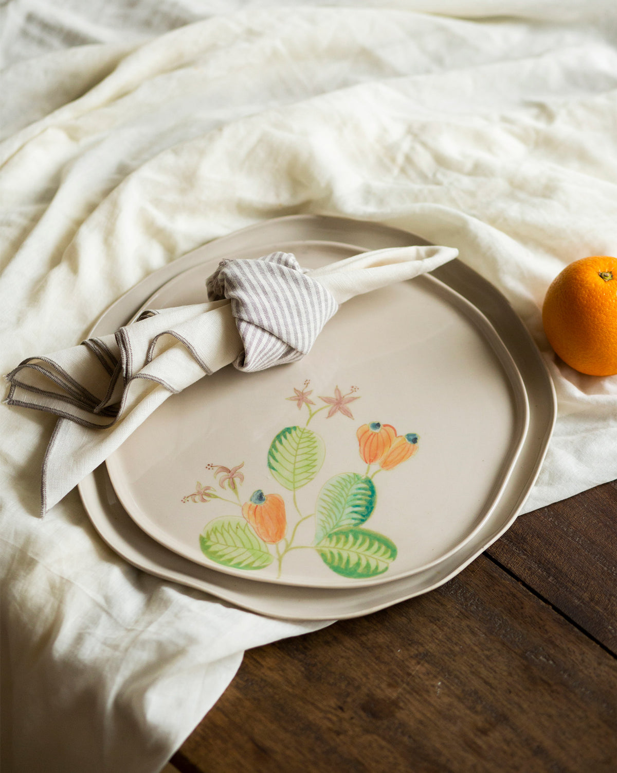 Mandovi Dinner Plate stacked on a second plate, showing the orange and green motif.