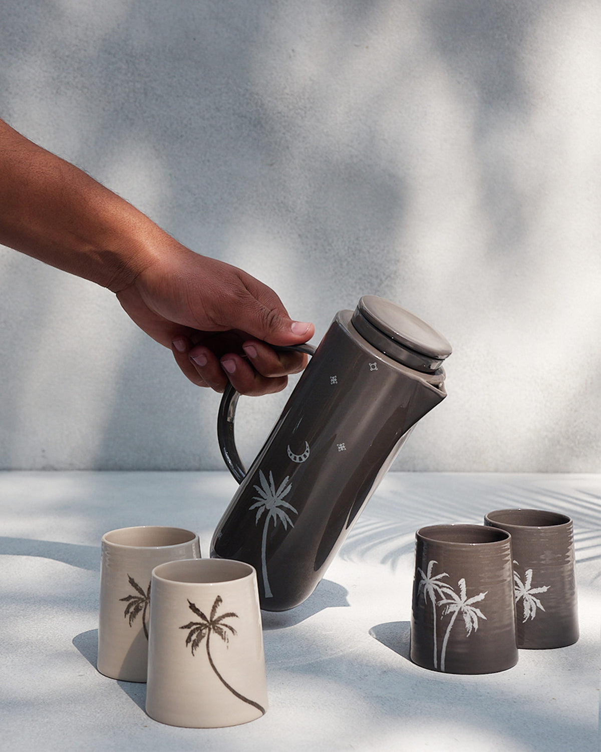 Taramandal Carafe pouring into cups with palm motifs.