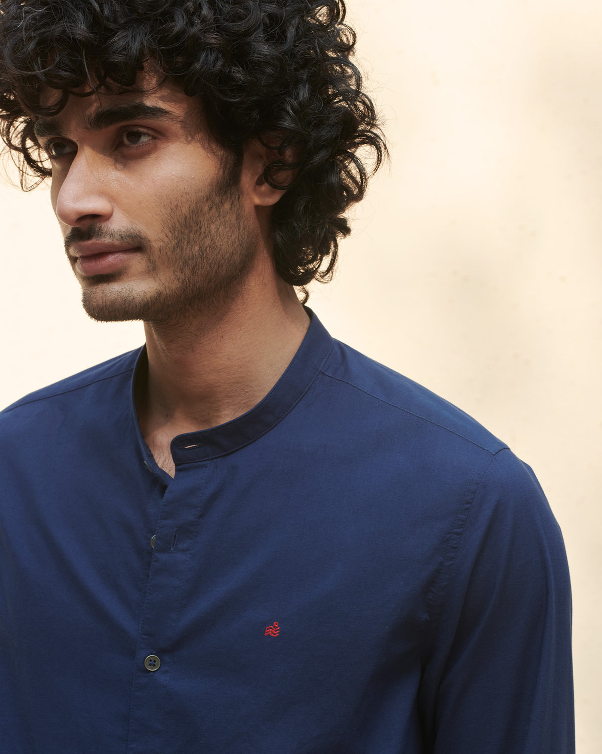 Close-up of a navy Nawab Shirt showing the band collar and red chest embroidery.