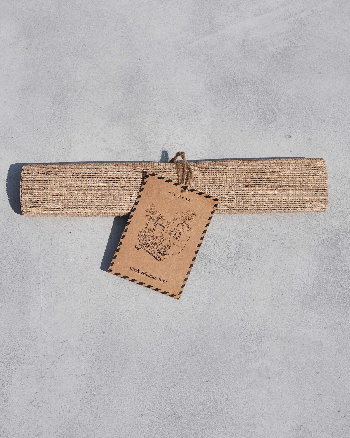 Rolled banana fibre runner with a Nicobar craft tag showing an elephant motif.