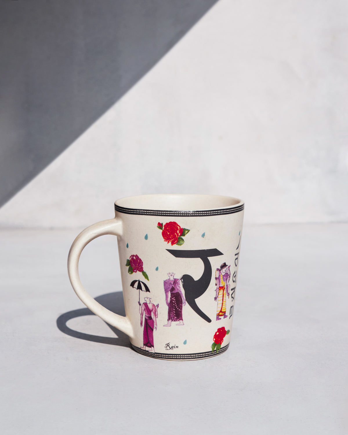 Ravenala mug with Devanagari letter, roses and rain illustrations.
