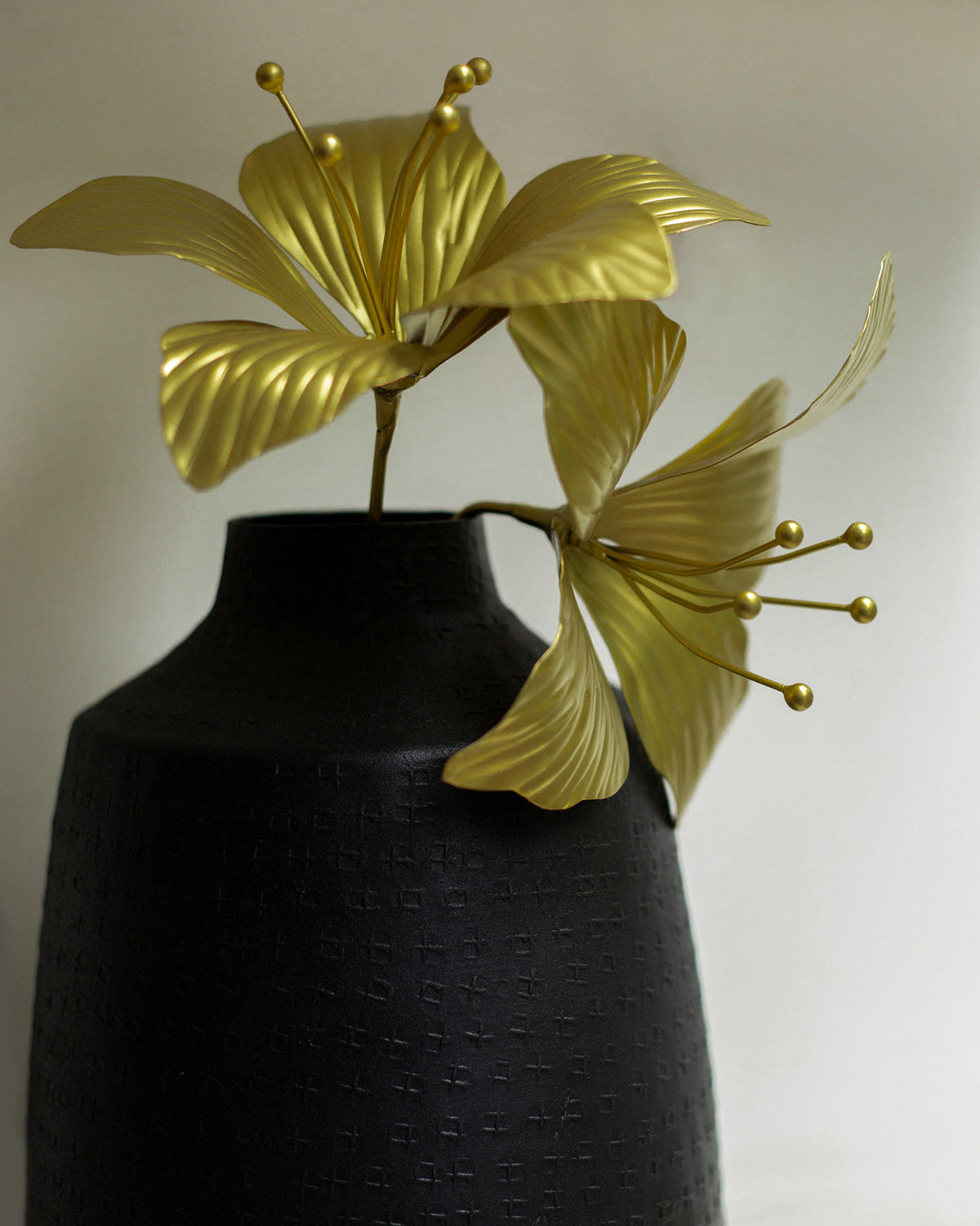 Close-up of gold Kachnar flower accents in a textured black vase.