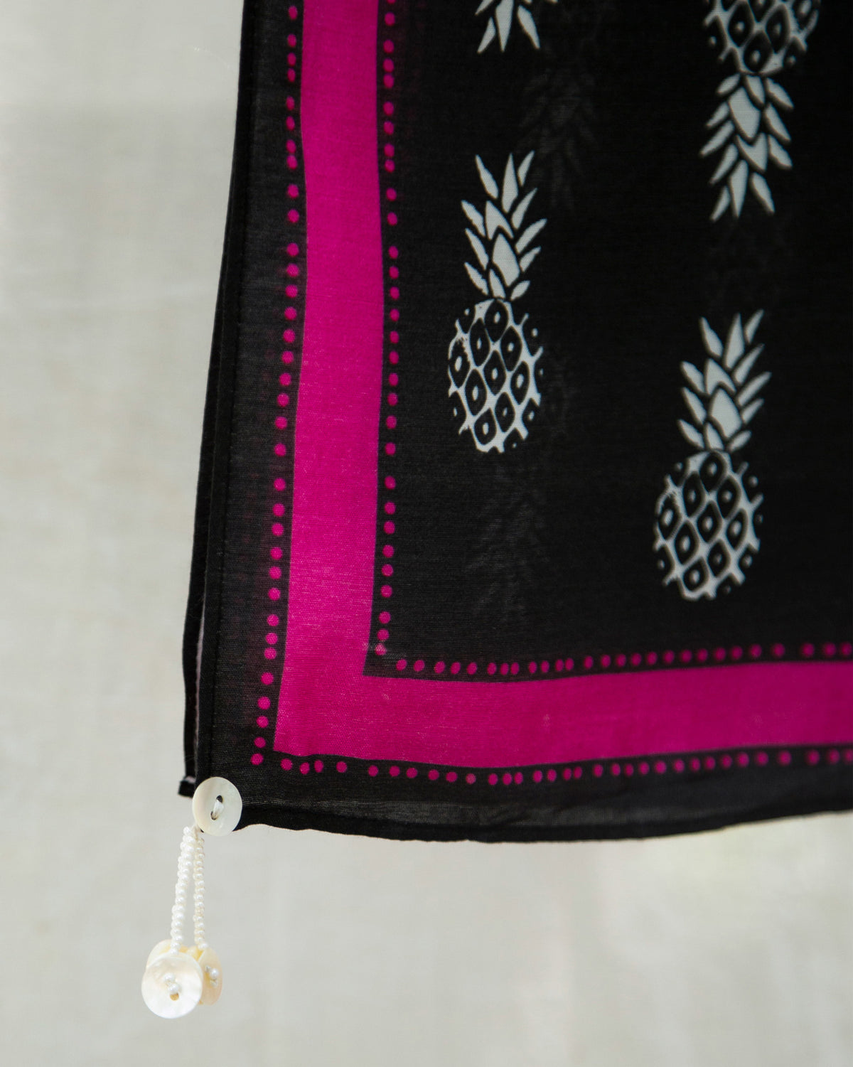 Close-up of the Tropico Scarf's black corner with pink border and pineapple motifs.