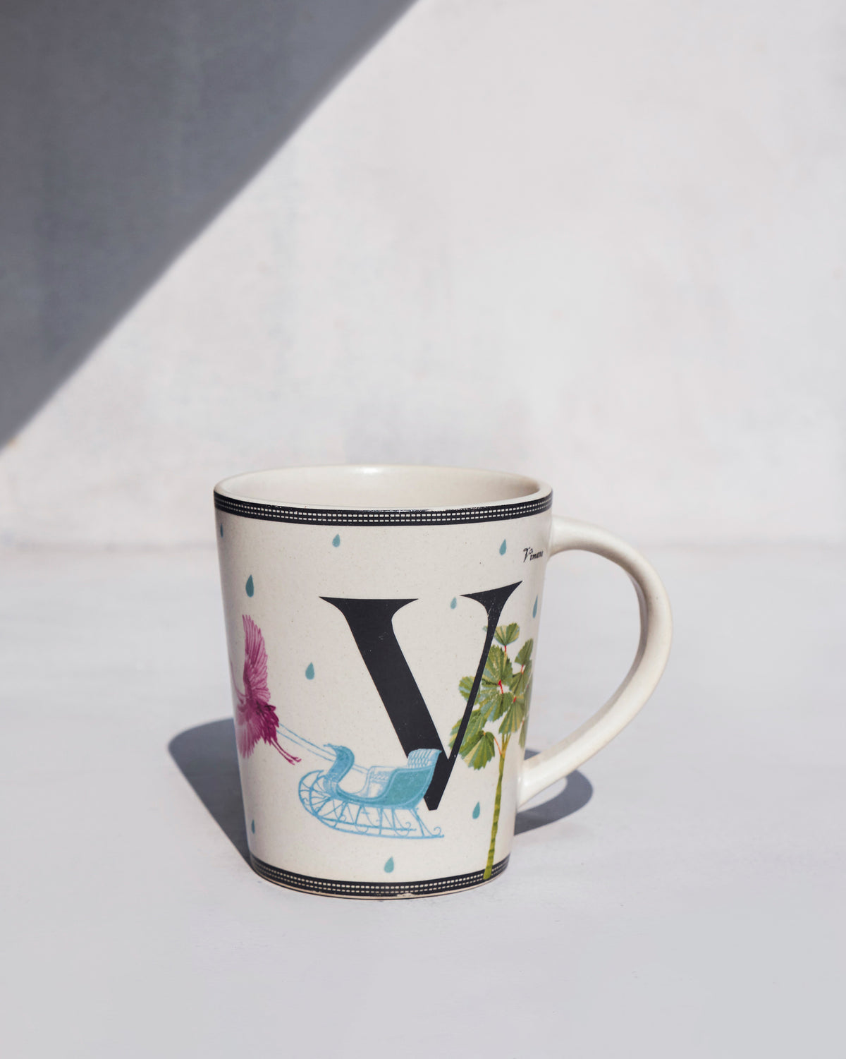 Cream Vriksh mug with a large V, bird and rickshaw motifs.
