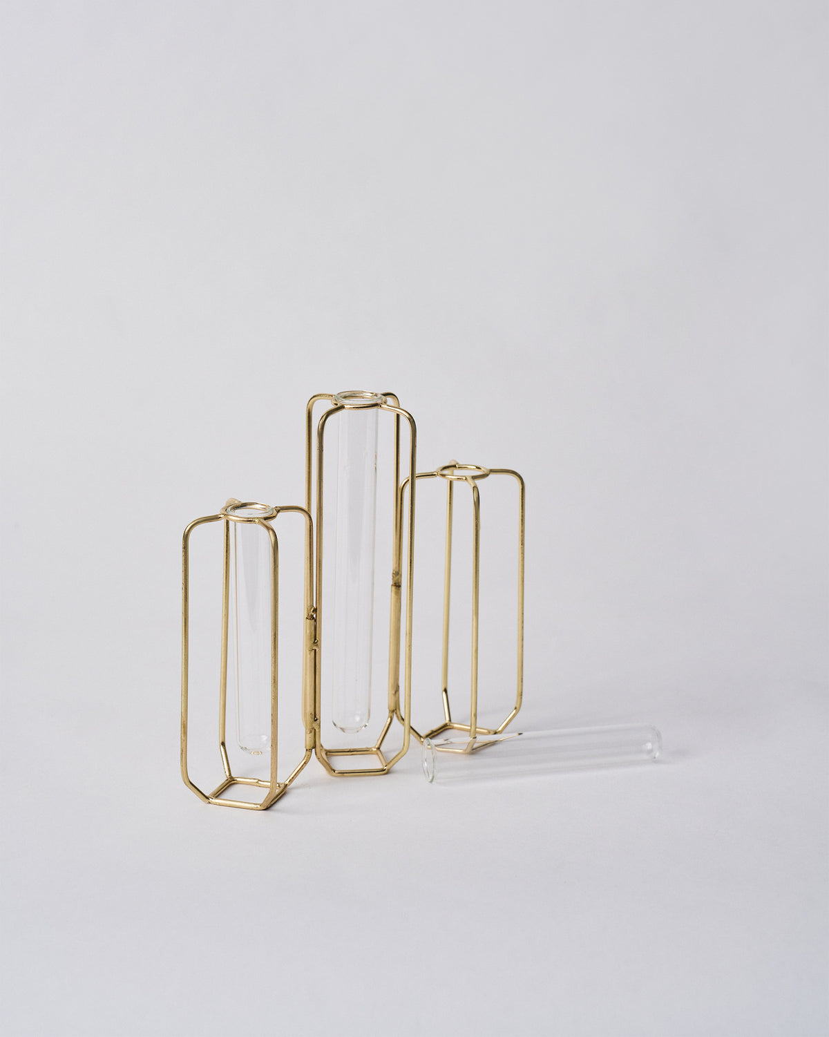 Gold wire test tube vases with one loose glass tube lying in front.