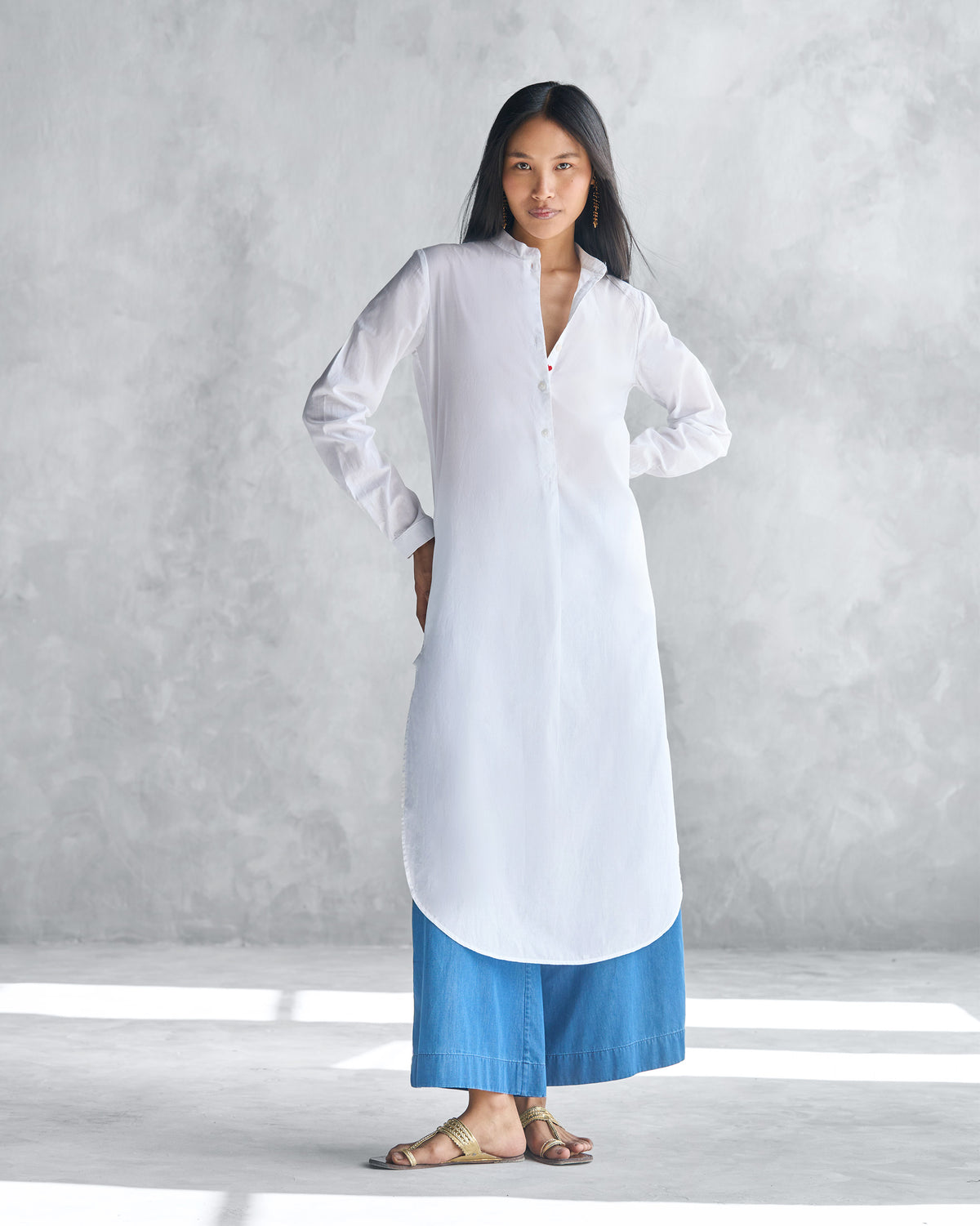 Person wearing a white long kurta with deep side slits and a shirt-tail hem.