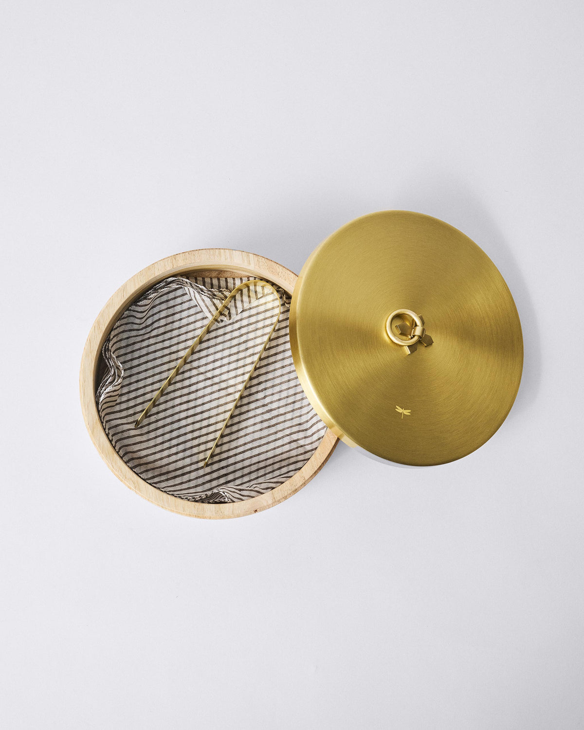 Open wooden roti box lined with a striped napkin, brass tongs and lid beside it.