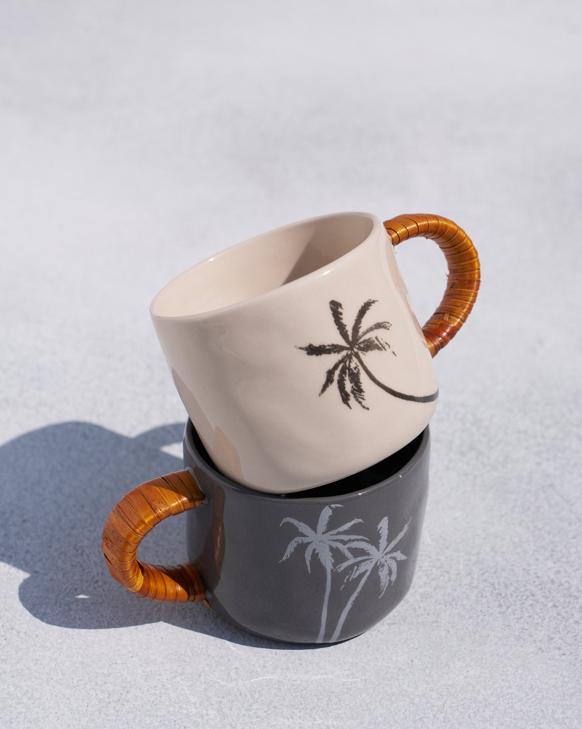 Ivory Mandovi mug stacked on a charcoal mug with rattan handles.