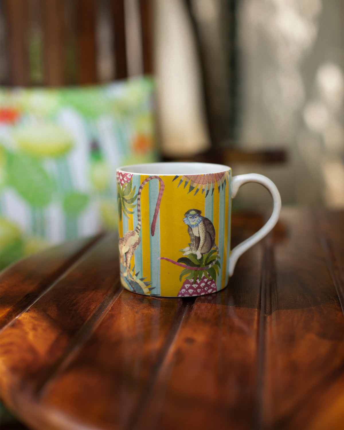Yellow Mahi Mug with a monkey and leaf print on a wooden table.