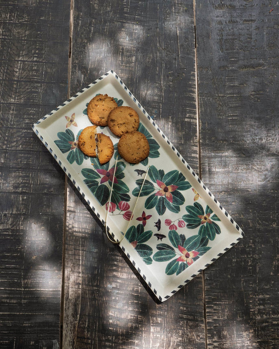 The Flora tray with cookies on a dark wooden table in dappled light