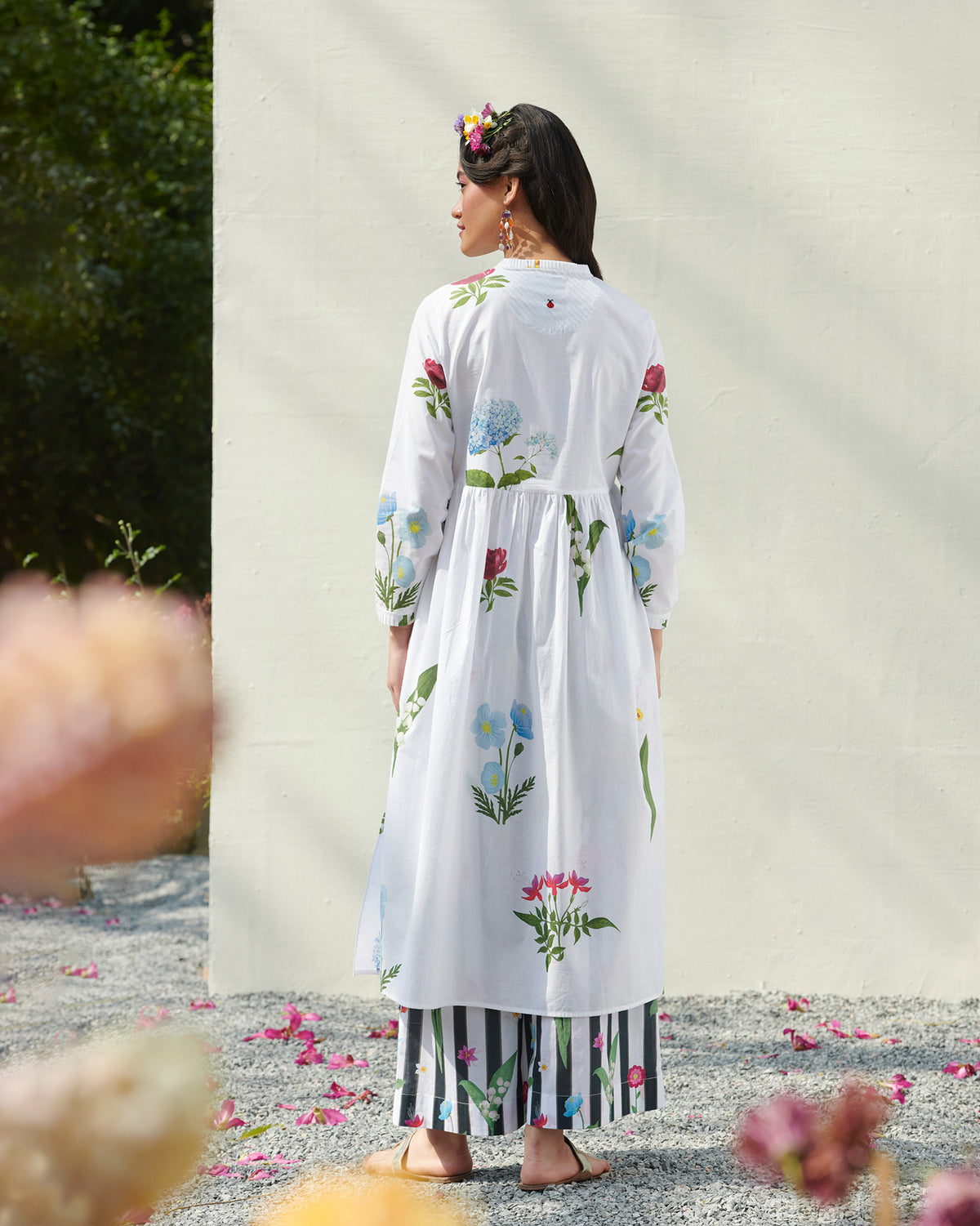 Back of a white pleat-front kurta with floral prints worn by a person.
