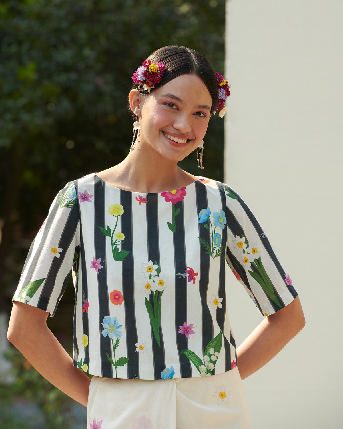 Person with hands on hips wearing a striped Boat Neck Blouse with floral print.