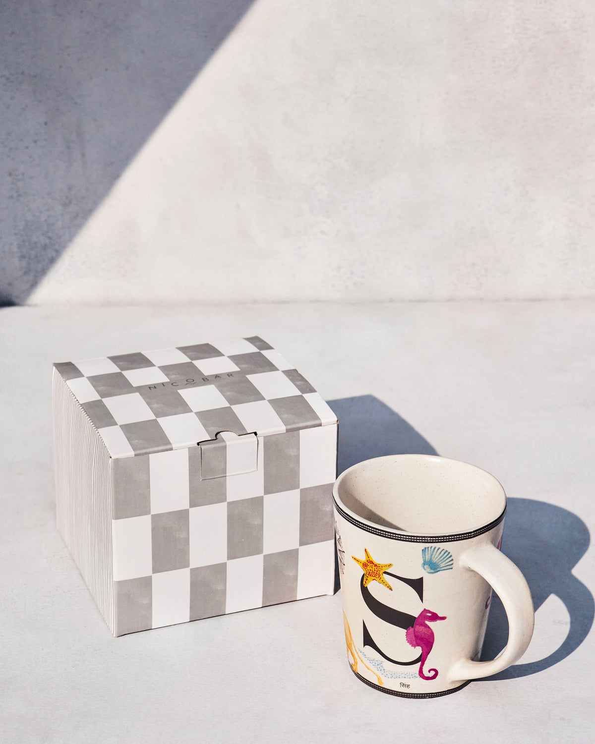 Singha mug beside its Nicobar checkerboard gift box.