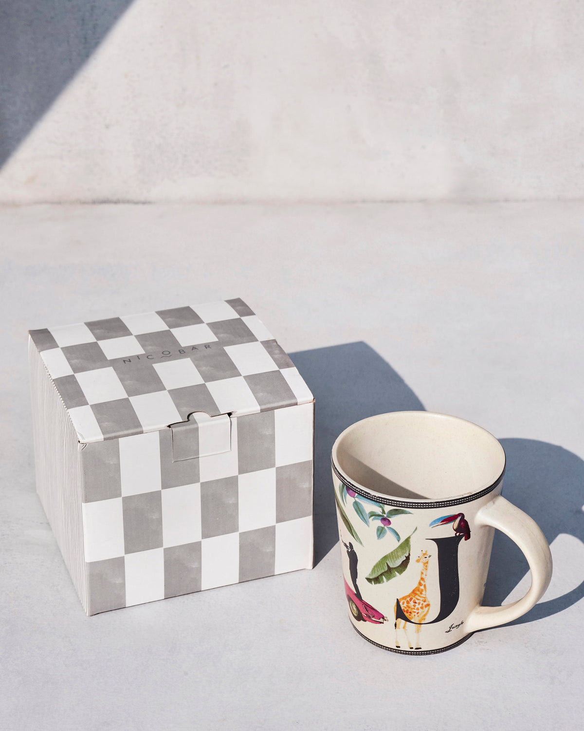 Jungle mug next to a checkered gift box.