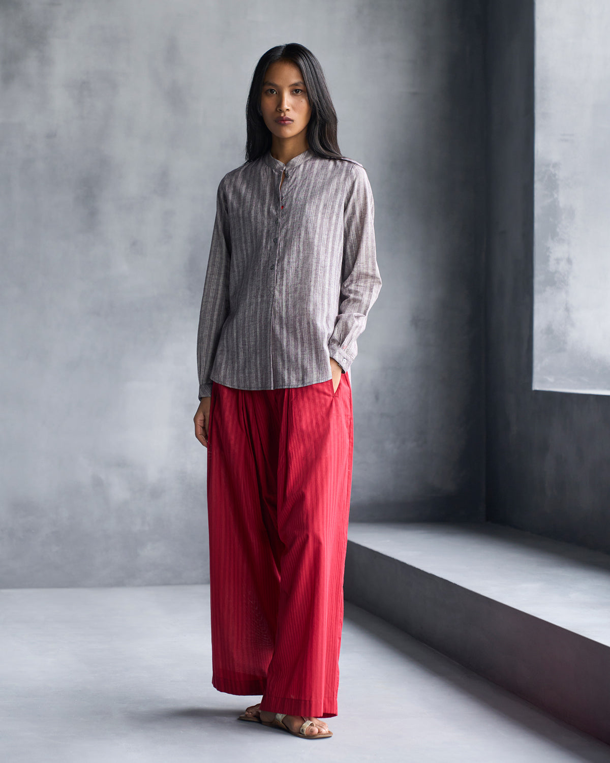 Person wearing a grey striped mandarin collar top with a relaxed hip-length fit.