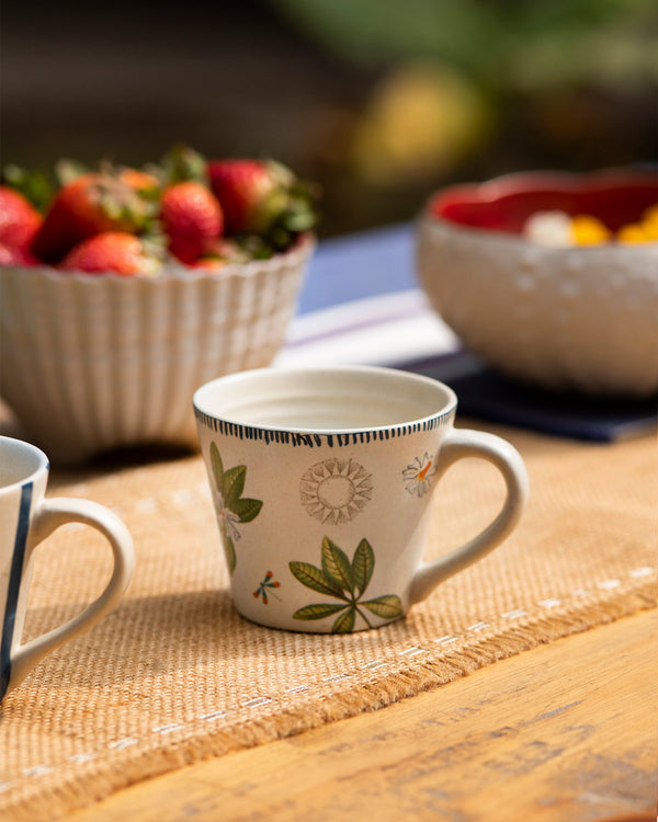 A cream mug with leaves and a dragonfly