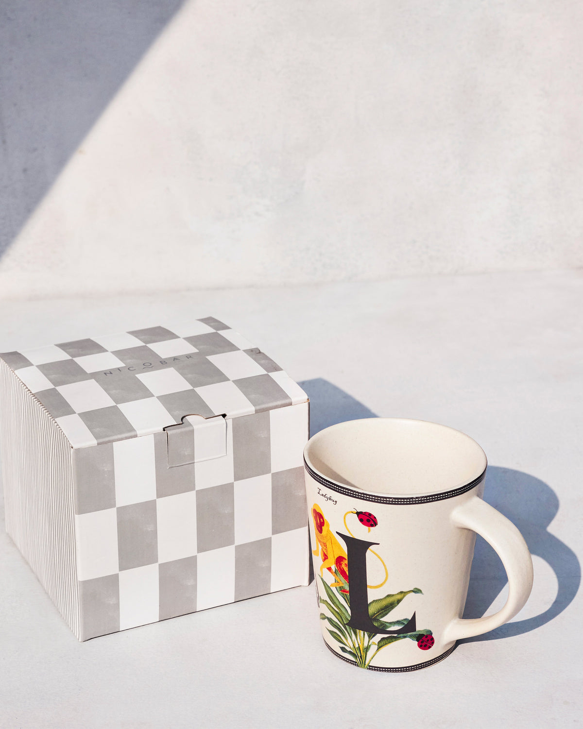 Cream Langoor mug with letter L beside a Nicobar gift box.