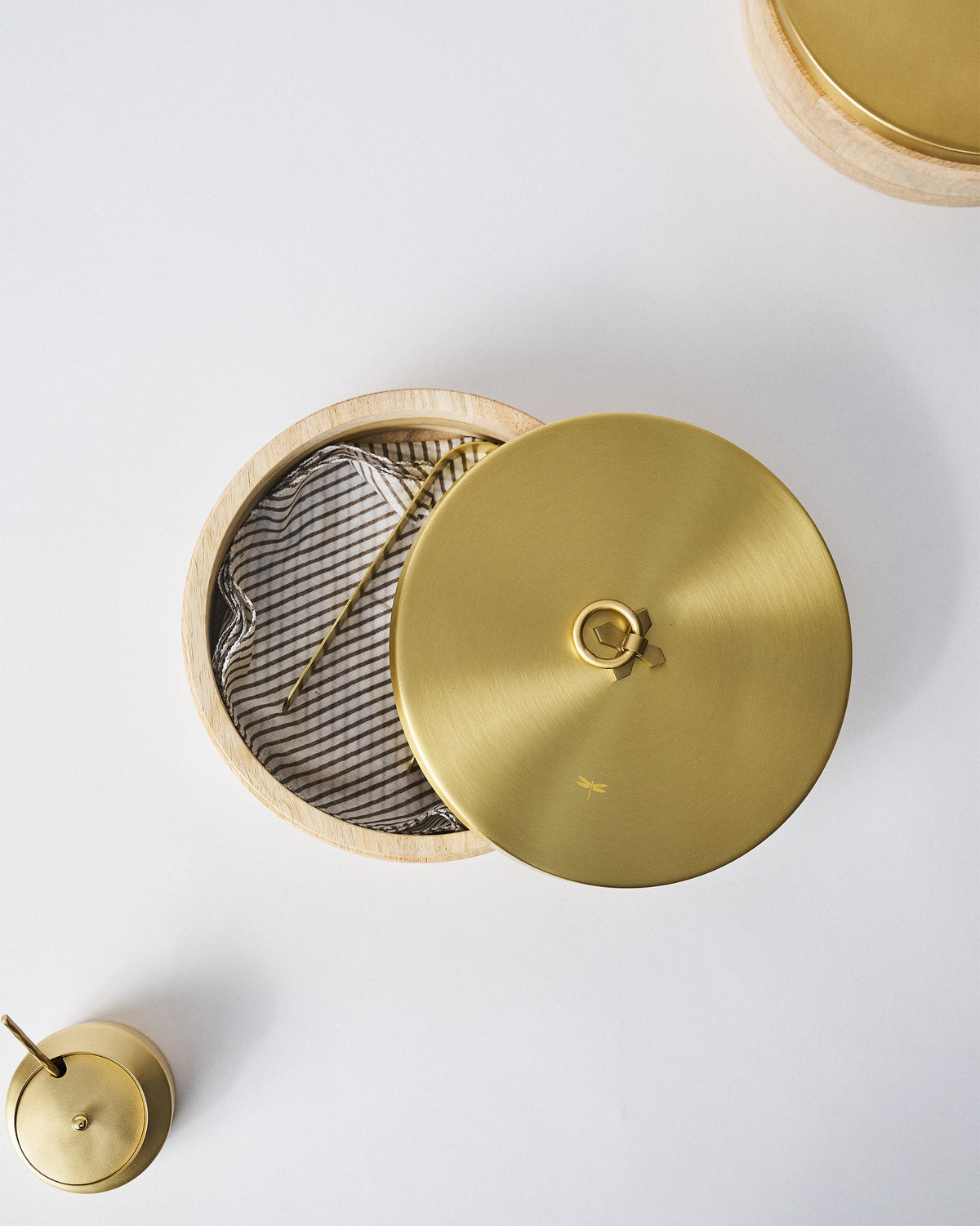 Wooden roti box with brass lid ajar over a candy-stripe napkin lining.