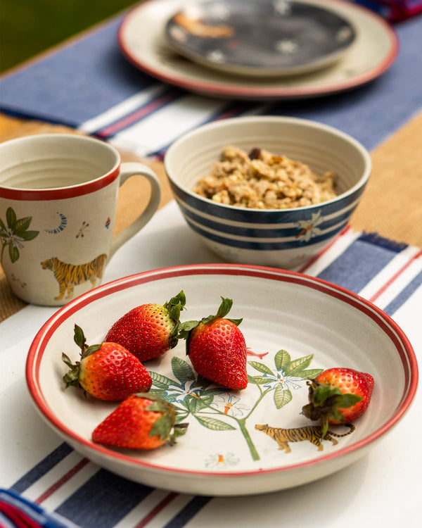 The bowl with strawberries beside a tiger mug