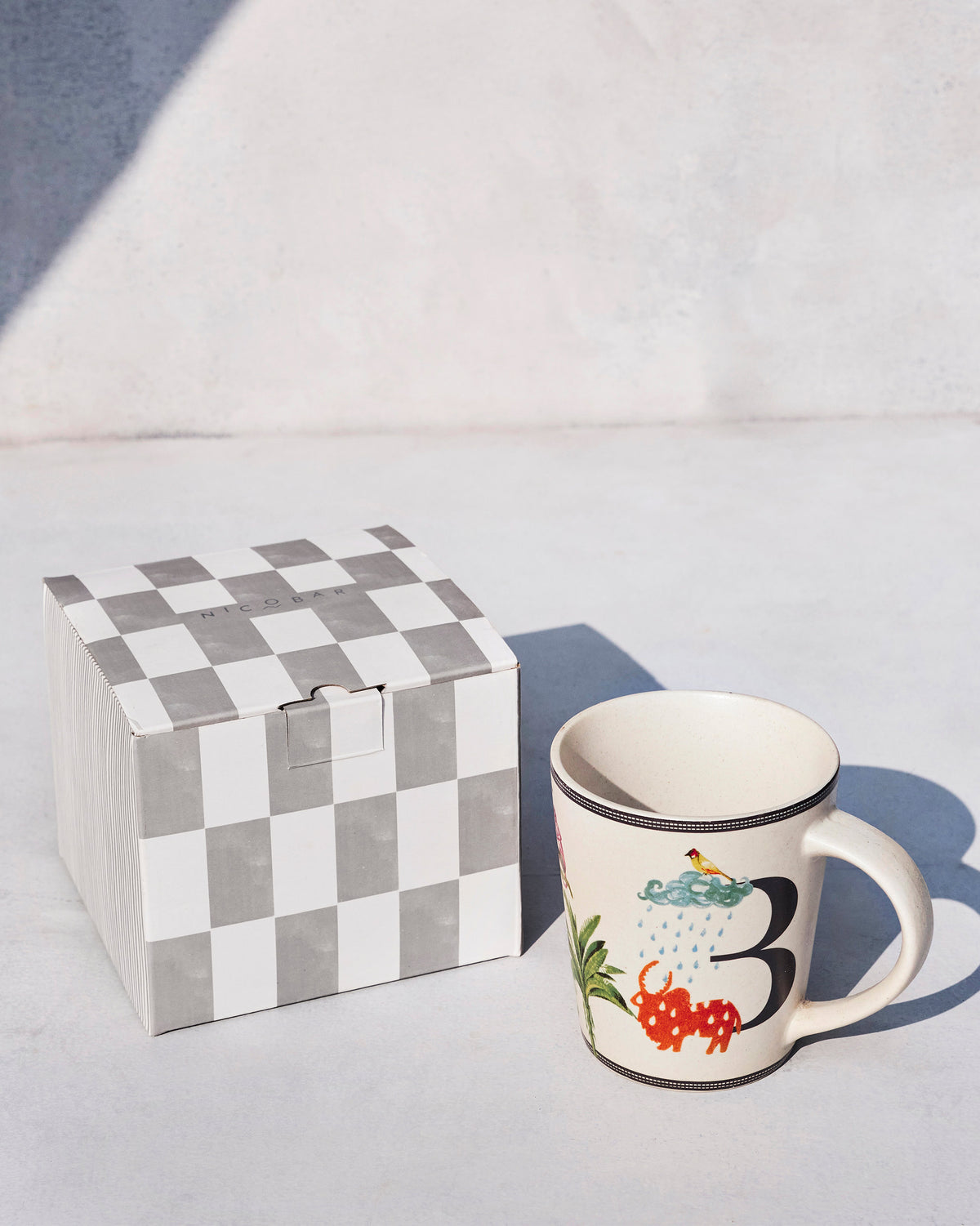 Badal mug with letter B beside its checkered Nicobar gift box.