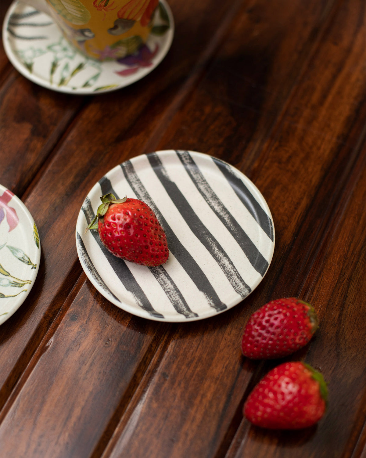 Close-up of a cream botanical coaster with thick black brushstroke stripes.