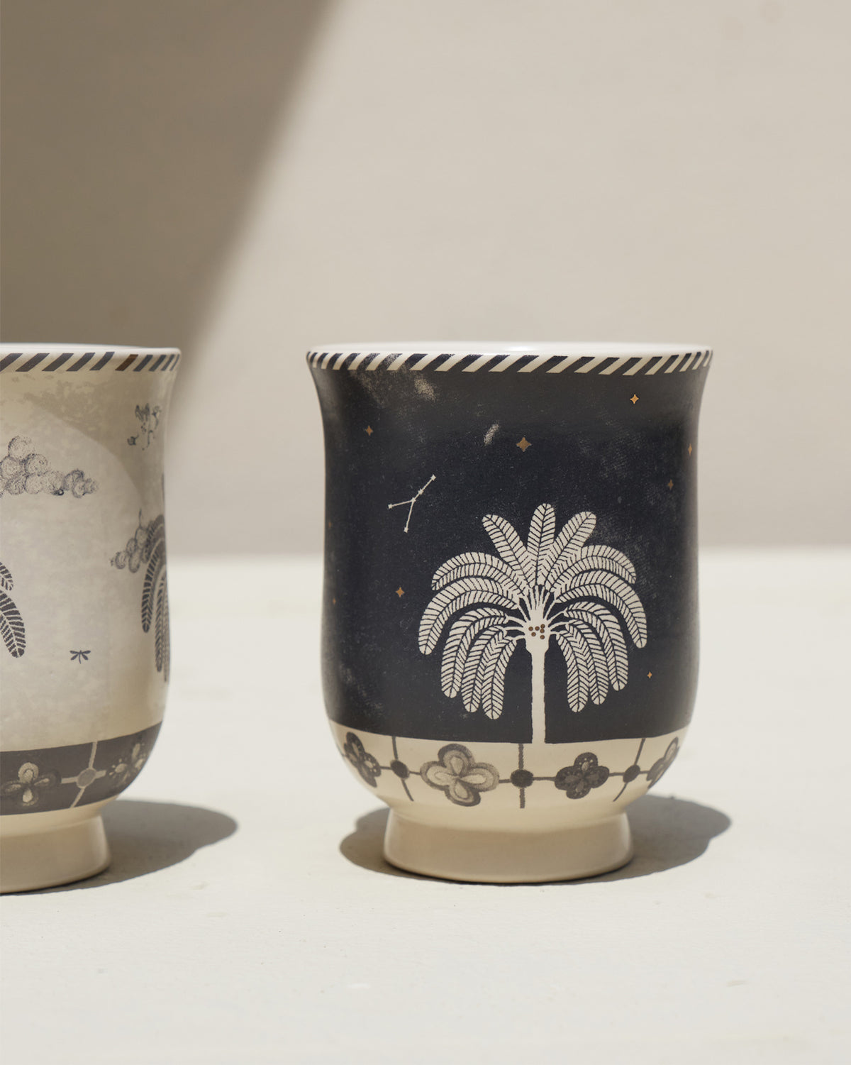 Side view of a navy Twilight Tea Cup with a palm tree and star motif.